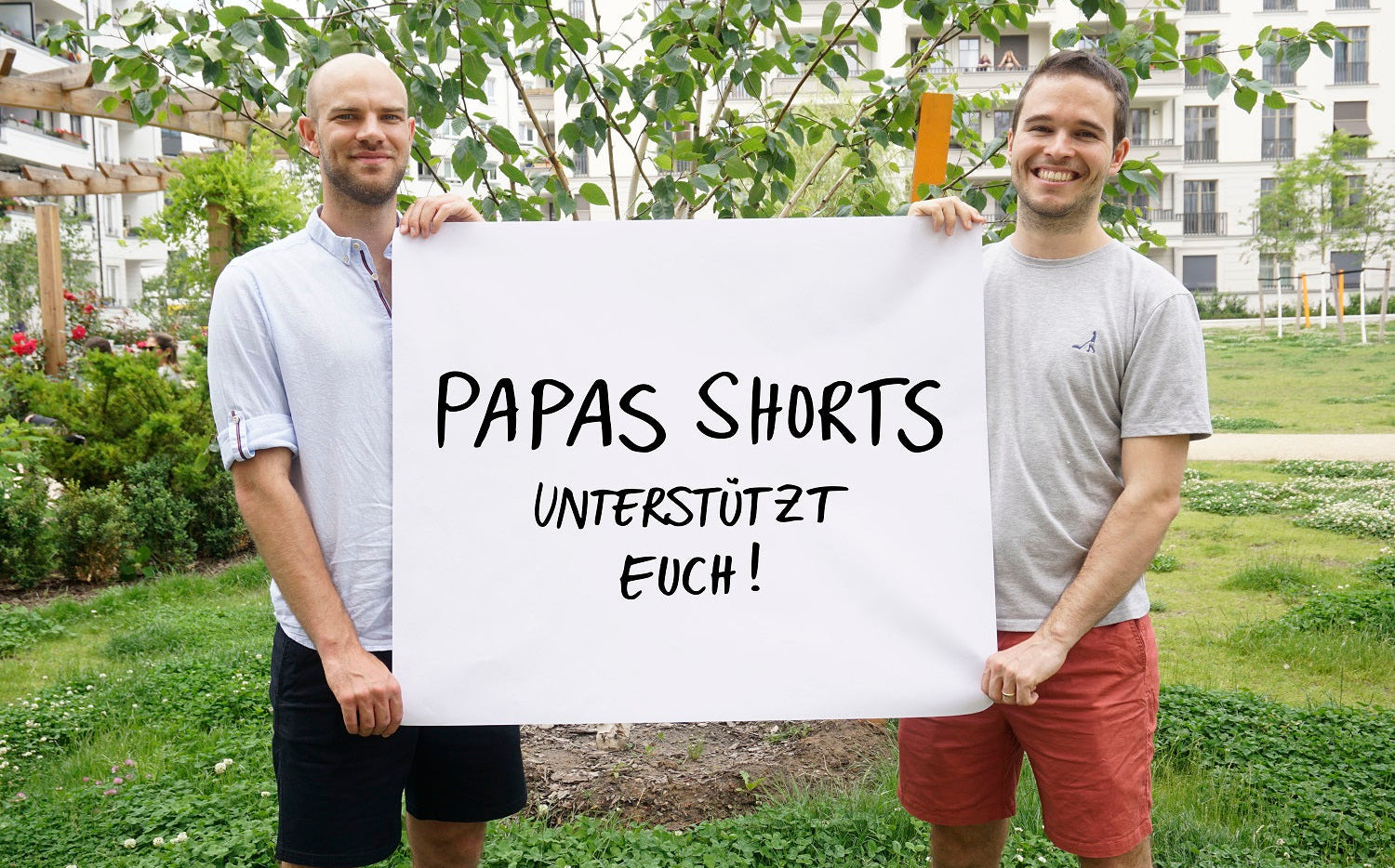 Tom und Robert halten ein Plakat für soziales Engagement hoch